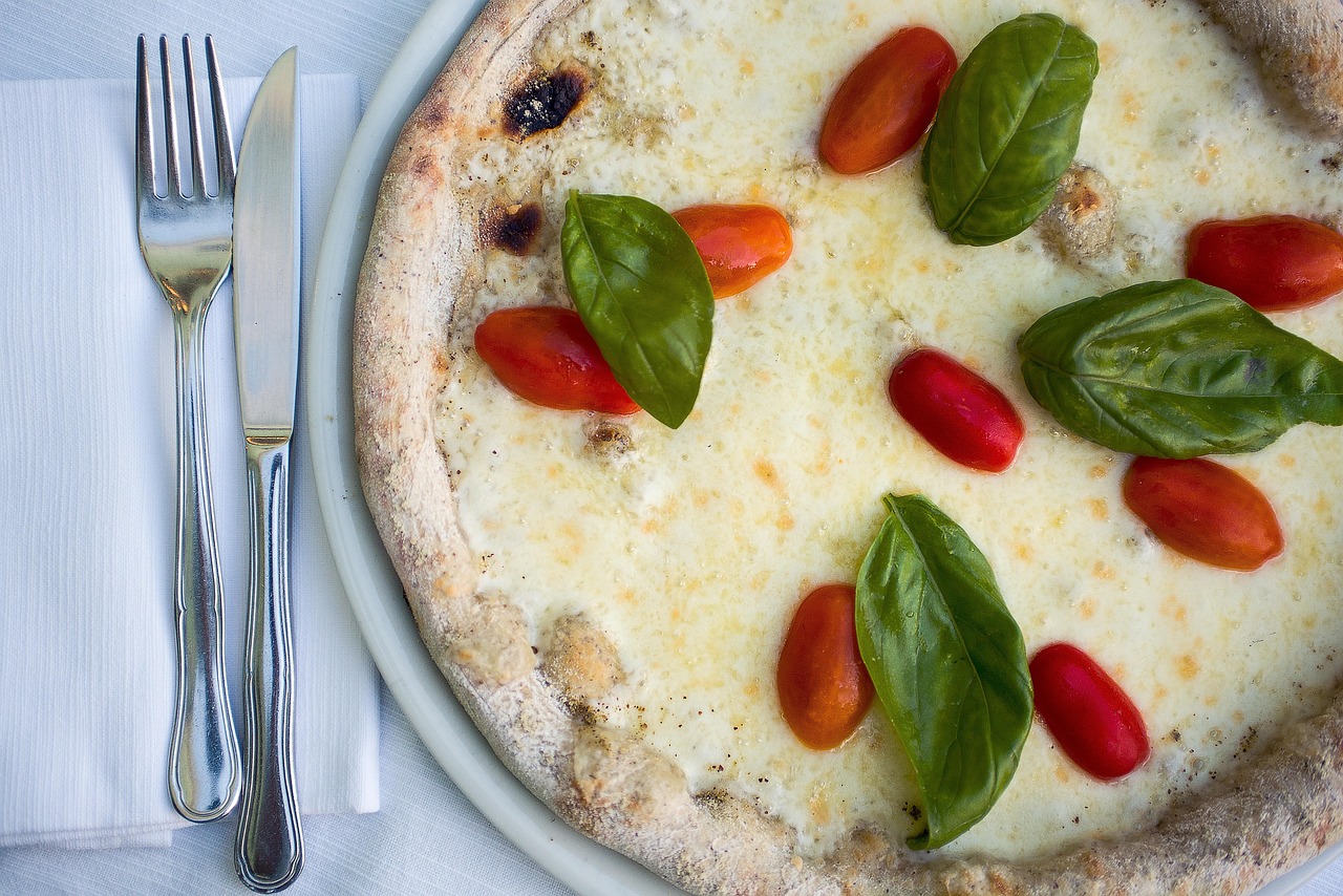 Pizza with mozzarella, cherry tomatoes and basil on a white plate