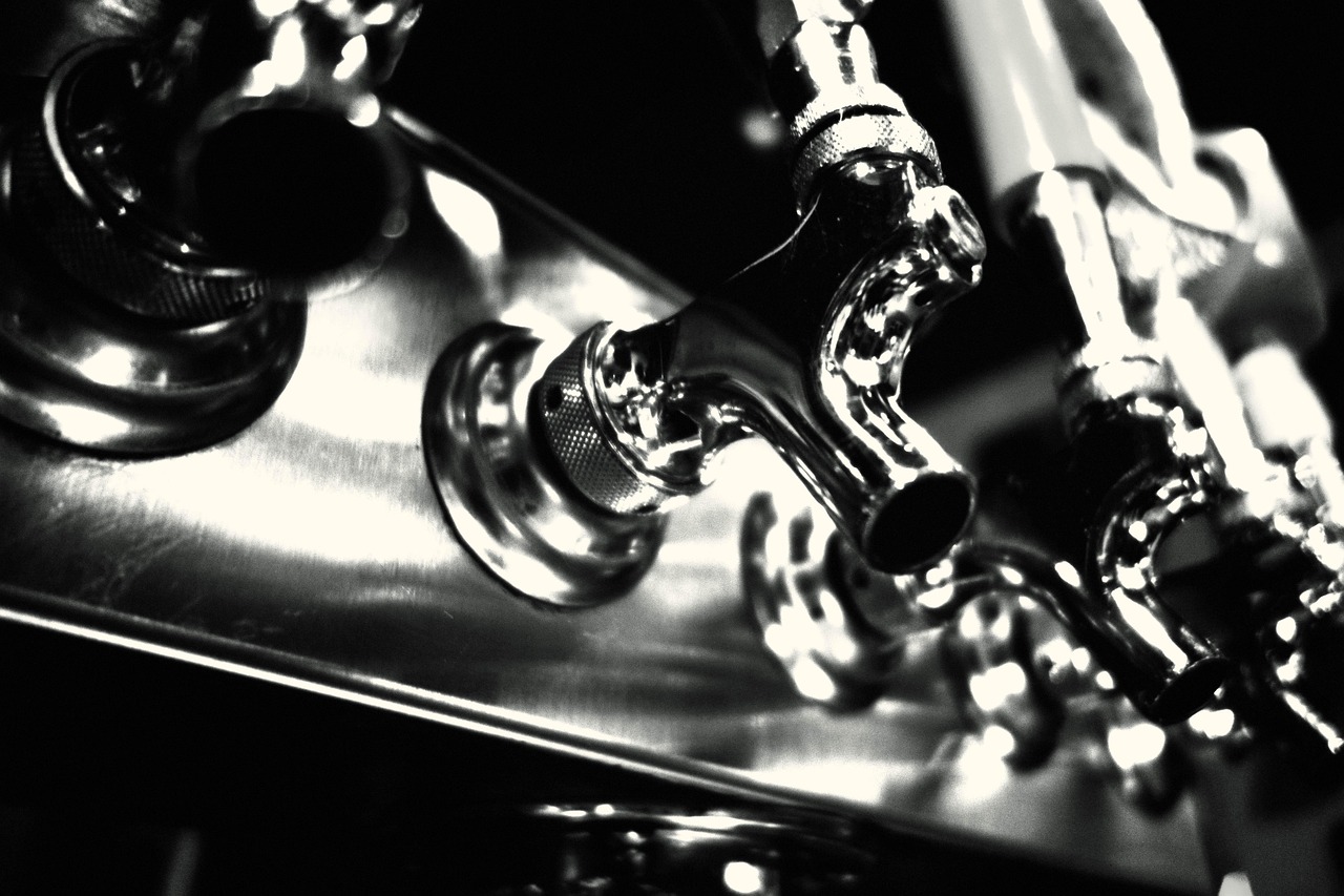 Close-up of chrome draft beer taps on a steel bar, shown in black and white